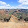 A large, rocky canyon with patches of grass and foliage and the shadows of clouds